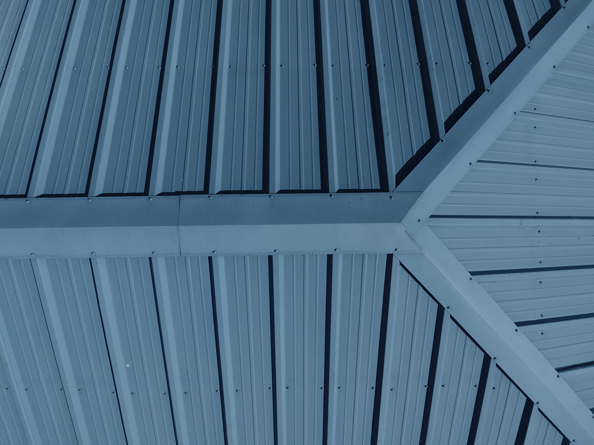 Metalldach aus blaugrauen Trapezblechen mit verschraubtem Firstblech